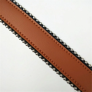 Close-up of brown pebbled leather strap featuring silver round studs and neat stitching