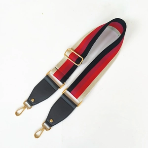 Detailed view of wide striped adjustable bag strap with golden rotating hooks