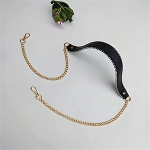 Detail of black leather handbag strap with gold metal chains and lobster clasp closure