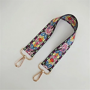 Detail eines breiten Schultergurts mit Blumenmuster und goldenen Karabinern