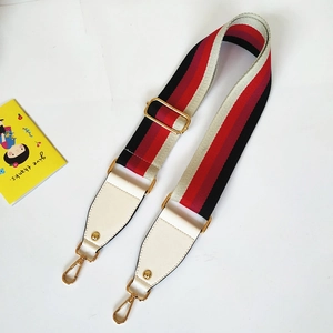 Close-up of wide striped woven bag strap with golden buckles and white leather ends