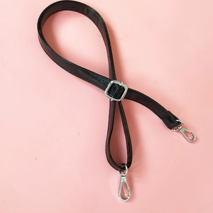 Detail of glossy black PU leather strap with adjustable silver buckle and lobster hooks