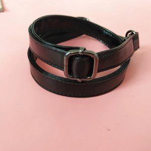 Detail of adjustable black patent leather shoulder strap with shiny mirror finish and buckle