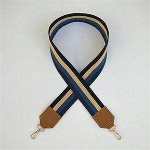 Detail des blau-beige gestreiften Taschenriemens mit Lederenden und goldenem Karabinerhaken