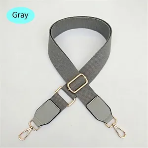 Detail view of adjustable grey canvas bag strap with golden metal buckle and hooks