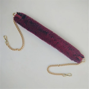 Detail of plush dark purple faux fur bag strap with gold metal chains and swivel hooks