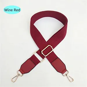 Macro detail of wine red canvas strap with gold lobster clasps and leather ends