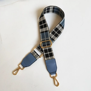 Detail of blue tartan canvas shoulder strap with gold metal hooks and blue leather ends
