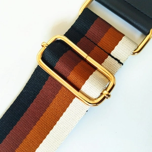 Close-up of adjustable striped handbag strap with gold buckle and high-density weave
