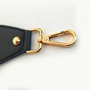 Detail of golden metal lobster clasp and black leather strap with precise stitching