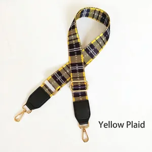 Close-up of yellow plaid woven bag strap with golden metal hooks and black leather ends