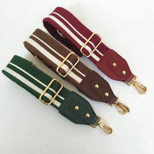 Close-up of three 5cm wide striped bag straps with leather ends and gold metal buckles
