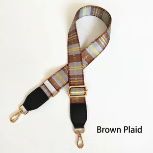 Detailed view of adjustable brown and blue plaid woven bag strap with golden hardware
