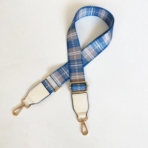 Detail view of adjustable blue and grey checkered bag strap with gold metal hooks