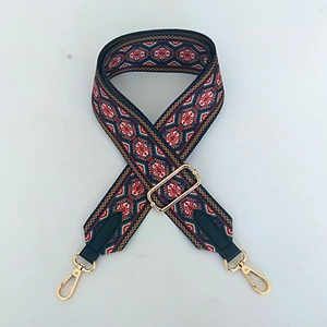 Detail eines geometrisch gewebten Taschenriemens mit goldenen Karabinerhaken