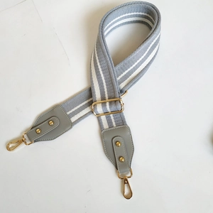 Close-up of adjustable striped cotton bag strap with gold metal hooks and leather ends