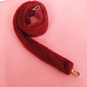 Detailed view of plush wine red faux fur handbag strap with golden circular metal clasps