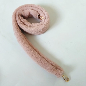 Detail of light pink faux fur bag strap with gold lobster clasps and soft texture