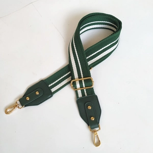 Close-up of green and white striped woven strap with gold metal hooks and leather details