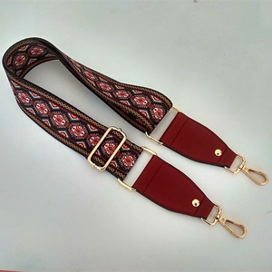 Close-up of ethnic jacquard woven bag strap with red leather ends and gold metal hooks