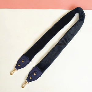 Detail of dark blue plush faux fur shoulder strap with gold metal carabiner hooks