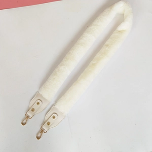 Detail of white faux fur bag strap with cream leather ends and gold lobster clasps