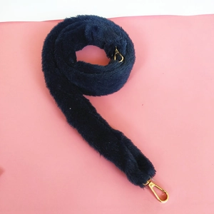 Detail of navy blue faux fur bag strap with golden metal lobster clasps on pink background