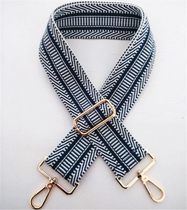 Close-up of navy blue and white striped woven bag strap with light gold metal hardware