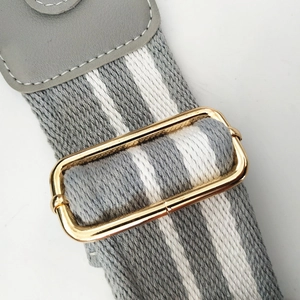 Detail of adjustable 5cm striped bag strap with gold buckle and grey leather connector