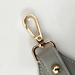 Detail of adjustable gray leather strap with gold lobster clasp and fine white stitching