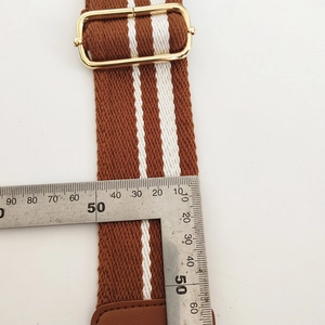 Detailed view of 50mm wide adjustable striped canvas strap with gold metal buckle