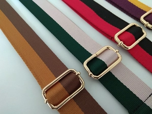 Detail of colorful striped woven bag straps featuring adjustable gold metal buckles