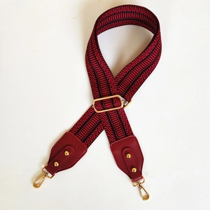 Adjustable woven shoulder strap for bags with red and black geometric patterns and gold clips
