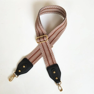 Detail of adjustable wide bag strap with brown and white chevron pattern and gold hooks