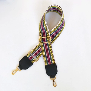 Close-up of ethnic style embroidered colorful woven strap with black leather and gold hooks