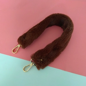Détail d'une bandoulière en fausse fourrure marron foncé avec fermoirs mousquetons dorés
