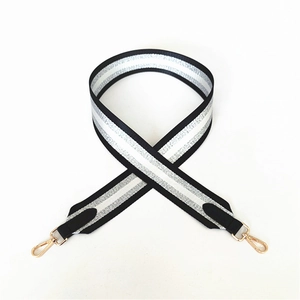 Detail of wide woven bag strap with silver sequins, black stripes and gold metal hooks