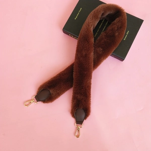 Close-up of fluffy dark brown faux fur bag strap with gold lobster clasps and leather ends