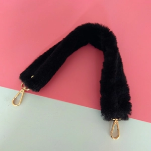 Détail d'une bandoulière en fausse fourrure noire avec mousquetons en métal doré clair
