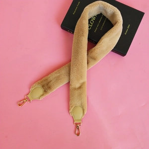 Detail view of plush faux fur handbag strap in camel brown with golden metal clasps
