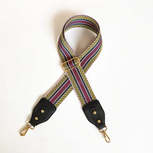 Close-up of colorful geometric woven shoulder strap with gold hardware on white background