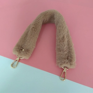 Détail de la anse en fausse fourrure marron clair avec mousquetons dorés sur fond pastel