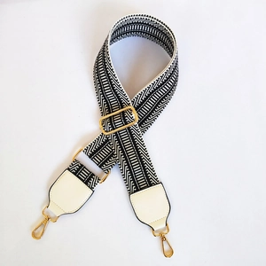 Detail of black and white geometric woven strap with gold lobster clasps and leather ends