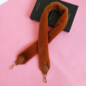 Brown faux fur bag strap with gold metal lobster clasps on a pink decorative background