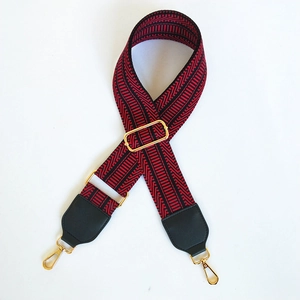 Adjustable wide embroidered bag strap with red and black geometric patterns and gold clips