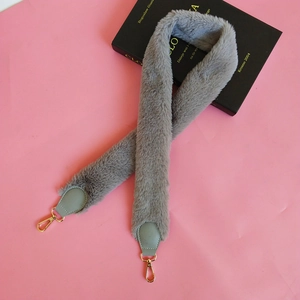Macro detail of soft grey faux fur shoulder strap with green leather and gold clips