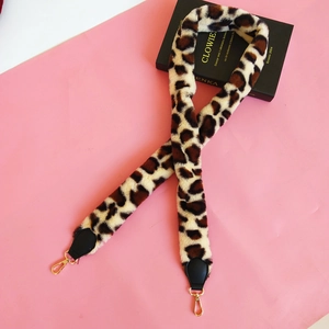 Detailed view of leopard print faux fur bag strap with gold lobster clasps and black leather