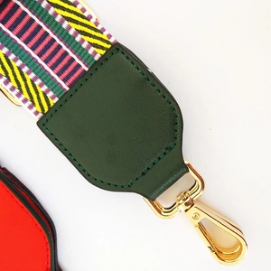Detail of multi-color woven bag strap with dark green leather end and gold metal hook