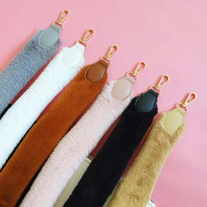 Multiple colorful faux rabbit fur shoulder straps with gold metal hooks on pink background