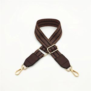 Detail of adjustable woven handbag strap with geometric pattern and golden metal clips
